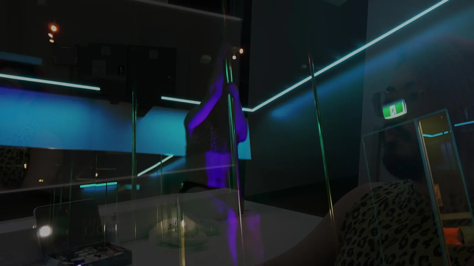 The Sydney Pole studio at night, lit in teal neon, with a dancer on the pole