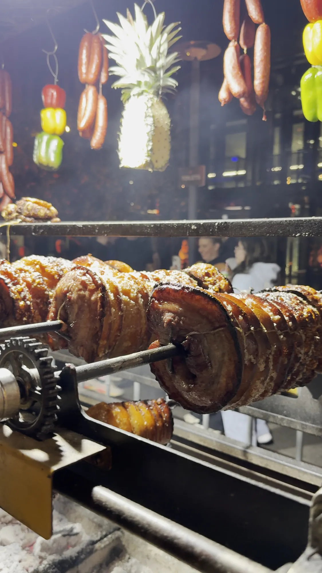 Festival moments: pork belly turning on the rotisserie, the hanging cooking line with pineapples, and the Vivid Fire Kitchen neon sign