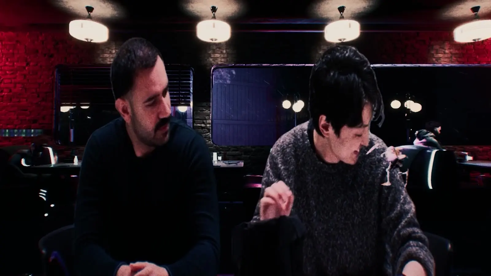 Two men talk across a table in a neon-lit diner