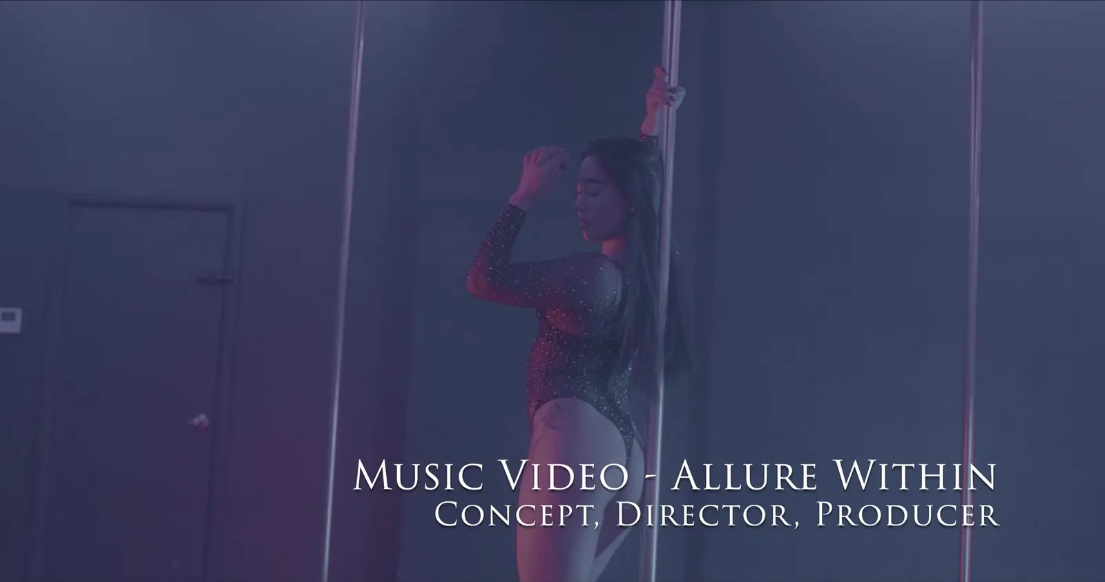 Uma pessoa dançando pole num estúdio iluminado de roxo, no videoclipe Allure Within